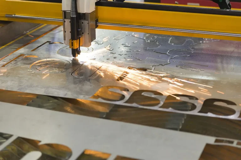 A CNC plasma cutting machine slices through a sheet of laser cut metal, producing bright sparks as it precisely cuts out numbers and letters.